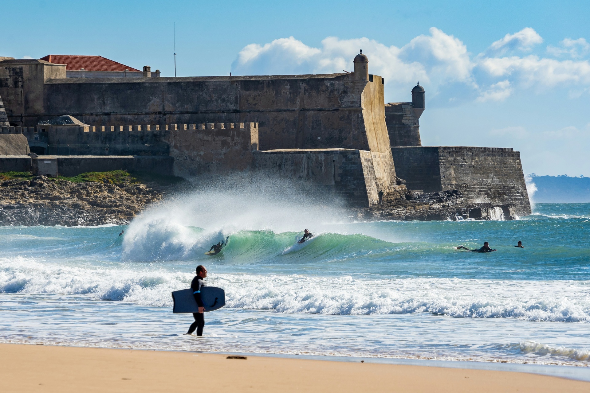 Surfer at Carcavelos beach with São Julião fort in the background